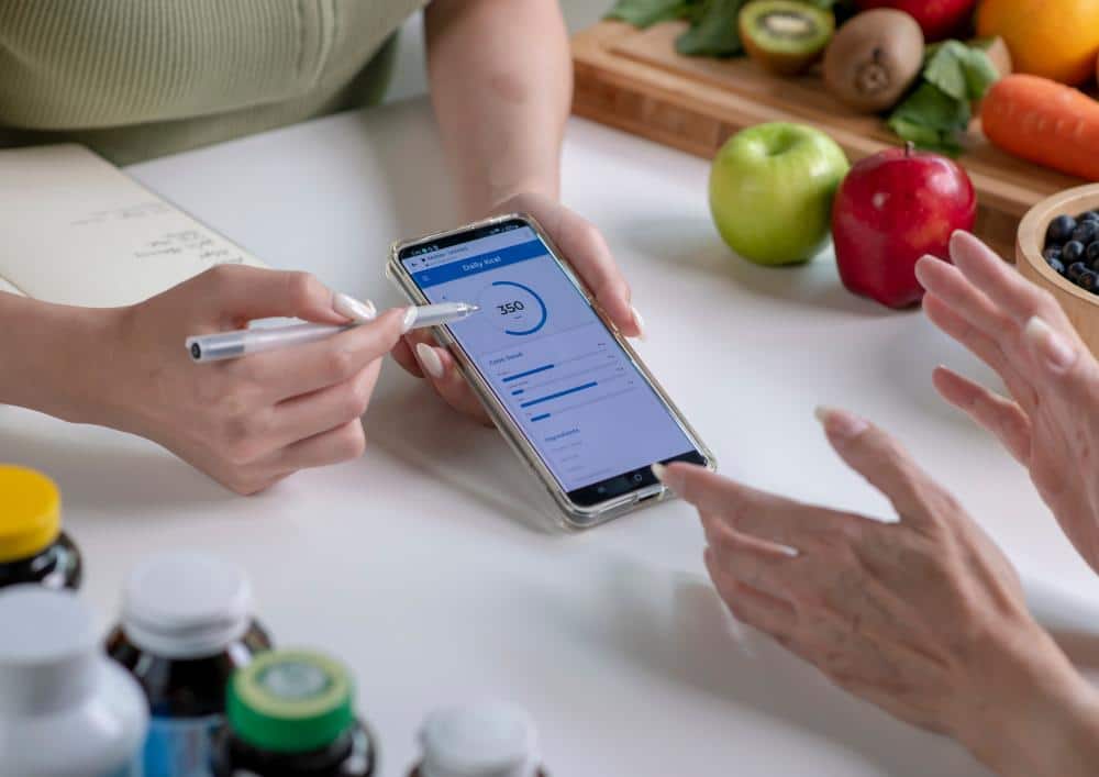 What Is A Clinical Nutritionist? 3 Two individuals using a smartphone to photograph their meal at a dining table.