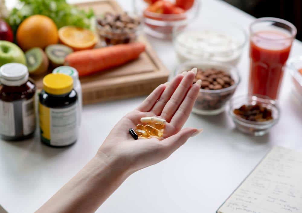 What Is A Clinical Nutritionist? 2 A person holds a vitamin pill above a table filled with various healthy foods, emphasising nutrition and wellness.