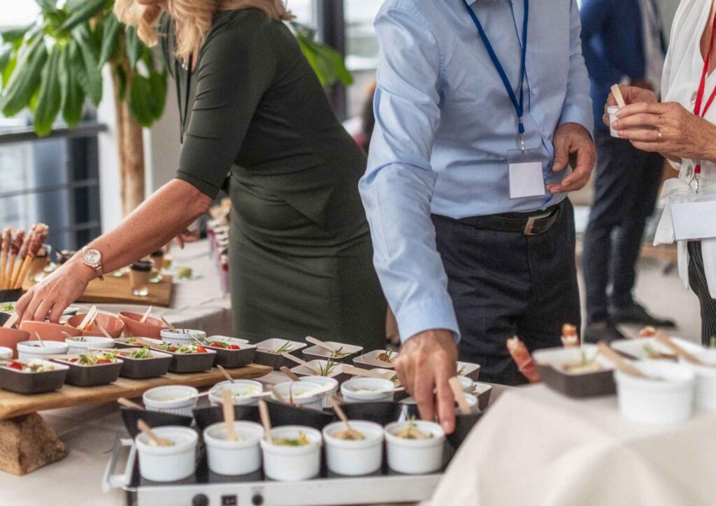 What Is Corporate Nutrition? 4 A group of people serving various dishes at a buffet table filled with food options.