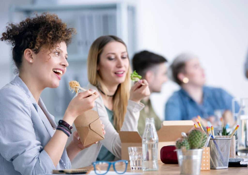 What Is Corporate Nutrition? 6 A diverse group of colleagues enjoying a meal together in an office setting, fostering teamwork and camaraderie.