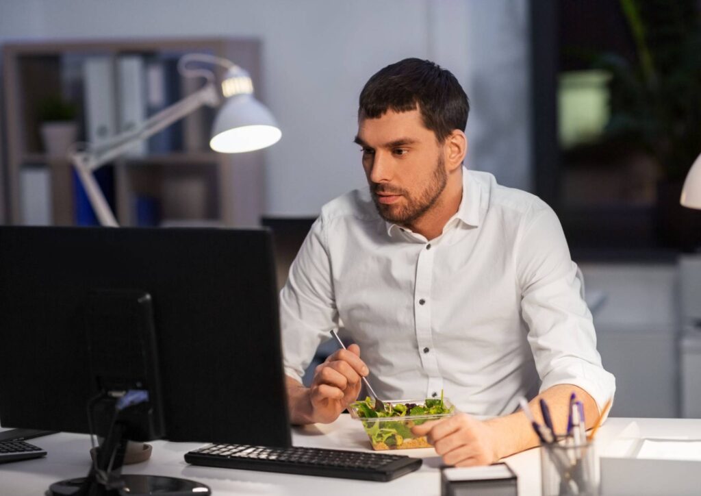 What Is Corporate Nutrition? 3 A man seated at his desk, enjoying a fresh salad during his workday.