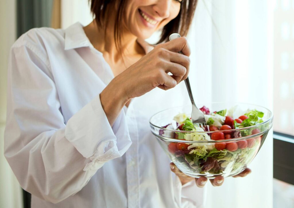 Corporate Nutrition Speaker Workplace Benefits 5 A woman holds a bowl of fresh salad, showcasing vibrant greens and colourful vegetables.