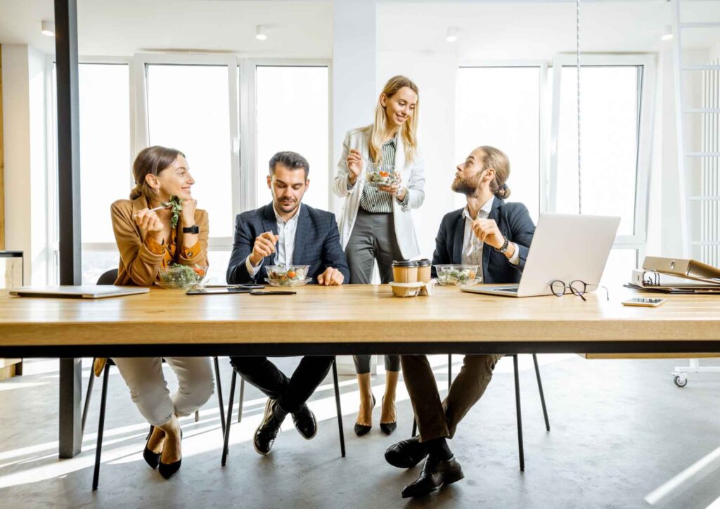Corporate Nutrition Speaker Workplace Benefits 1 A group of business professionals engaged in a meeting around a conference table in a modern office setting.