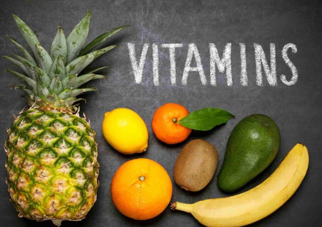 Nutrition For Runners 6 The word "vitamins" is written on a blackboard, surrounded by colourful vitamin bottles and capsules.