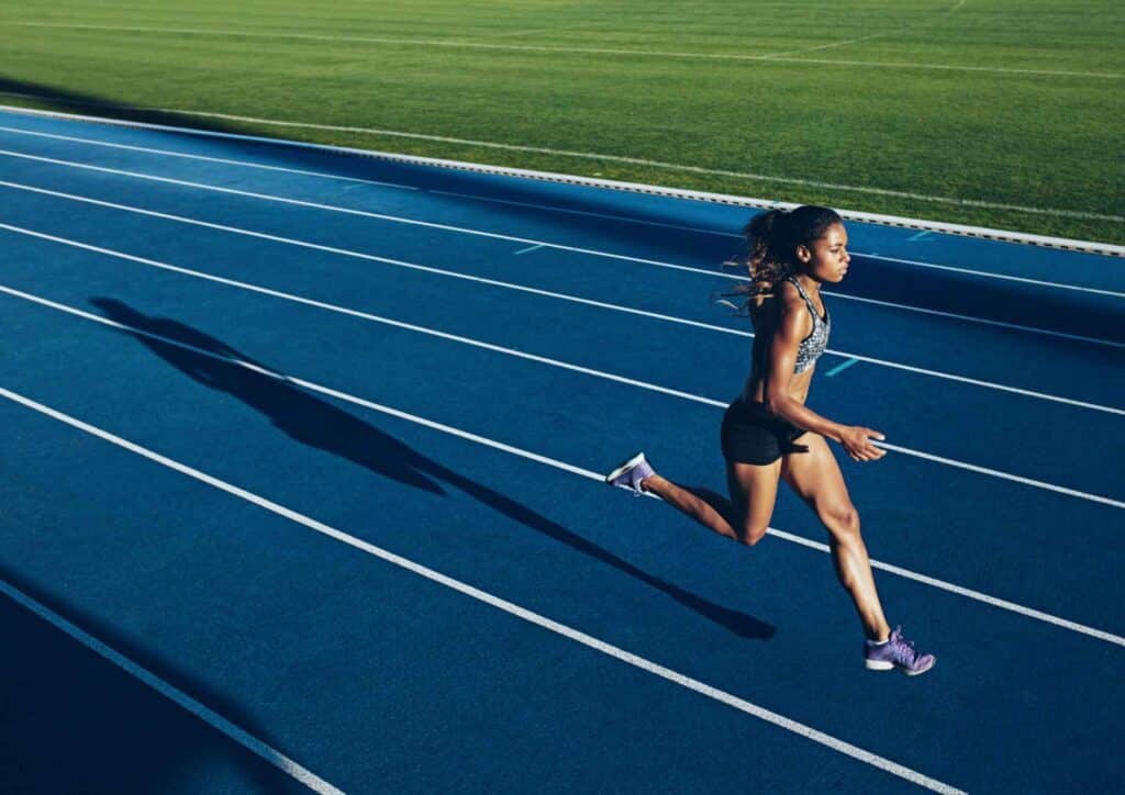 Nutrition For Runners 2 A female athlete sprinting on a blue running track, showcasing determination and athleticism.