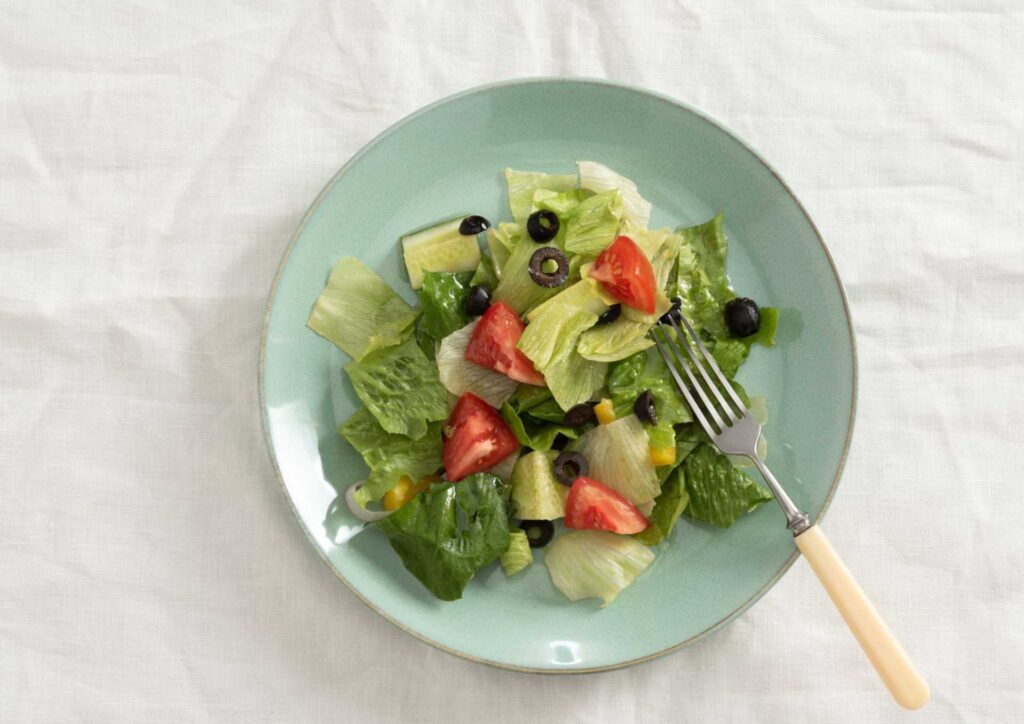 What Is The Perfect Diet? 2 A plate filled with a colorful salad accompanied by a fork resting beside it.