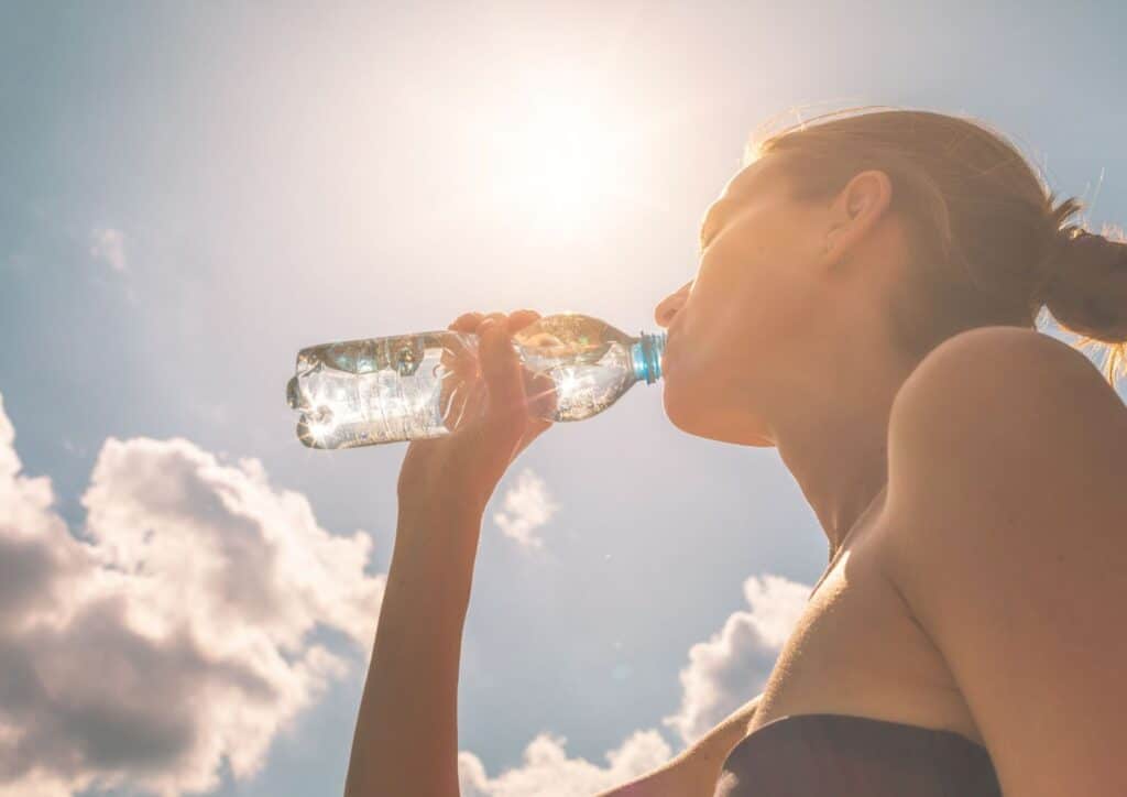 Nutrition For Runners 7 A woman takes a sip from a water bottle, promoting hydration and wellness.