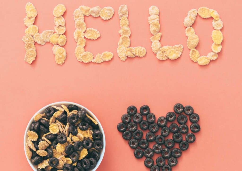 Is Breakfast the Most Important Meal of the Day? 7 Heart-shaped cereal pieces arranged on a pink background, conveying a playful and cheerful theme.