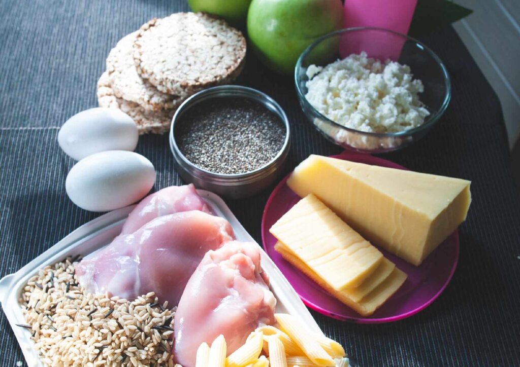 What Is A Sports Nutritionist? 3 A variety of fresh ingredients for a healthy breakfast, including fruits, oats, and nuts arranged on a wooden table.