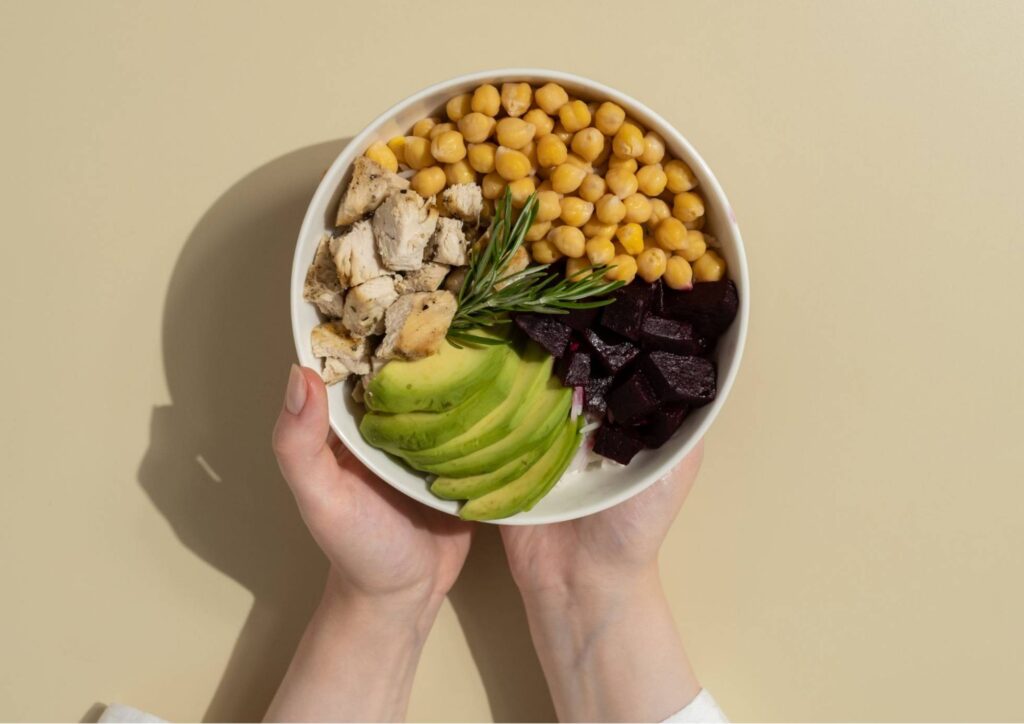 What Is A Sports Nutritionist? 11 A person holds a bowl filled with colorful vegetables and beans, showcasing a healthy meal option.