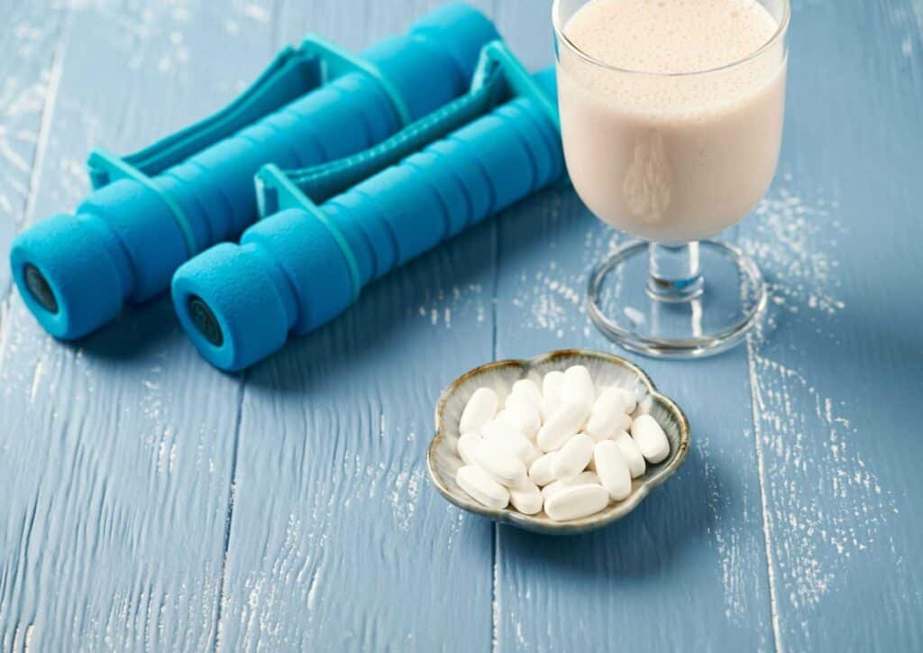 What Is A Sports Nutritionist? 12 A pair of dumbbells and a glass of milk are placed on a wooden table, suggesting a fitness and nutrition theme.