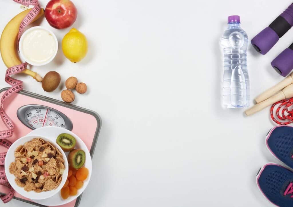 What Is A Sports Nutritionist? 7 A scale, water bottle, and assorted fruits arranged on a white background, emphasizing healthy lifestyle choices.