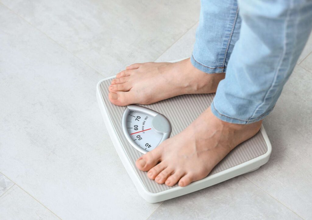 Can a Nutritionist Help to Lose Weight? 3 A person stands on a bathroom scale, measuring their weight in a home setting.