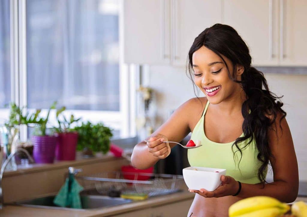 Are Oats Good for Weight Loss? 6 A woman in a sports bra enjoys a bowl of fresh fruit, highlighting a healthy lifestyle and nutritious eating habits.
