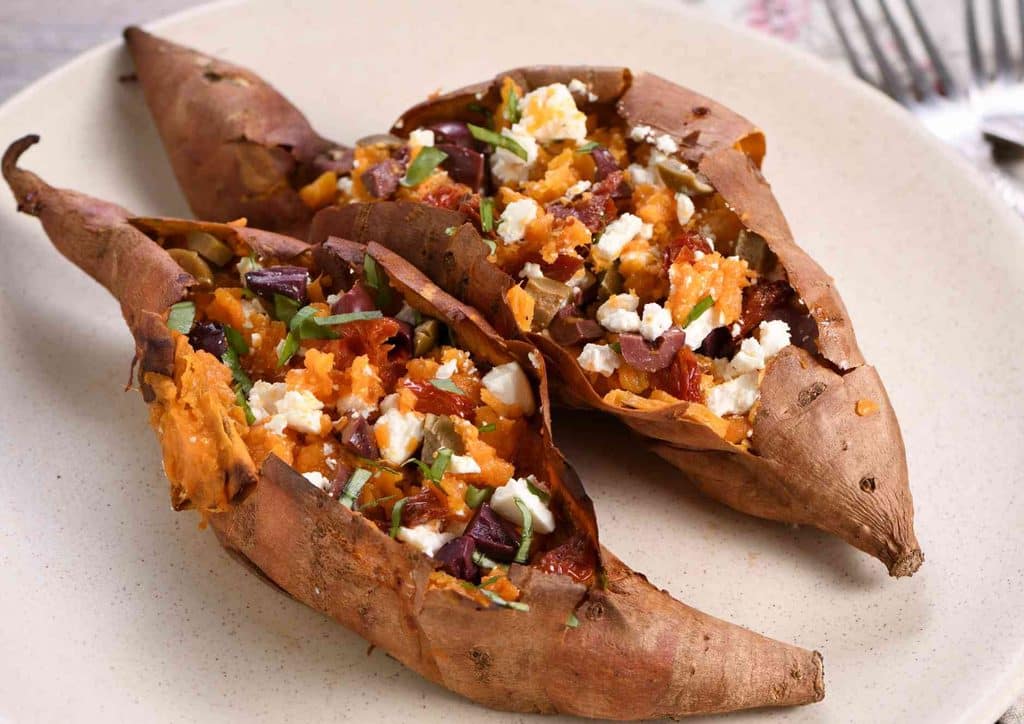 Is Sweet Potato Good for Weight Loss? 17 Two sweet potatoes cut in half, revealing their orange flesh and textured skin.