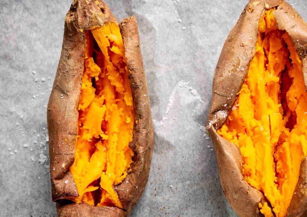 Is Sweet Potato Good for Weight Loss? 24 Two halved sweet potatoes with their insides exposed, showcasing the orange flesh and rough skin.