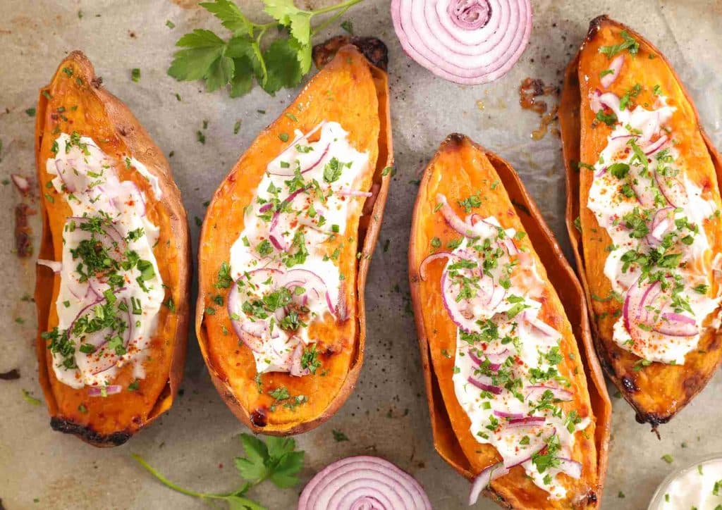 Is Sweet Potato Good for Weight Loss? 2 Four sweet potatoes topped with sour cream and chopped onions on a white plate.