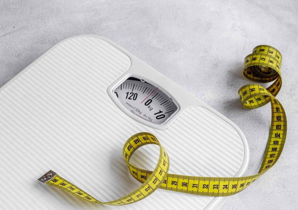 Do Chia Seeds Help With Weight Loss? 15 A weight scale and a tape measure placed on a white background, symbolising health and fitness measurement.