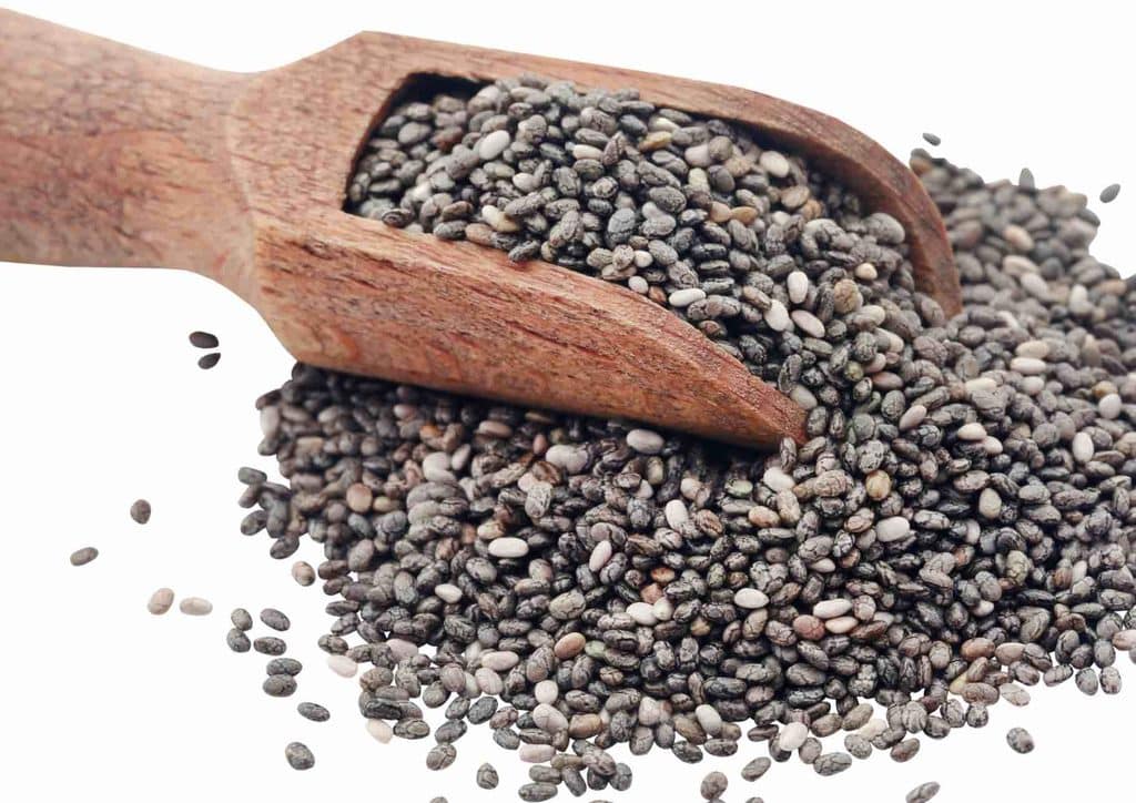 Do Chia Seeds Help With Weight Loss? 8 Chia seeds in a glass jar beside a wooden spoon on a light surface.