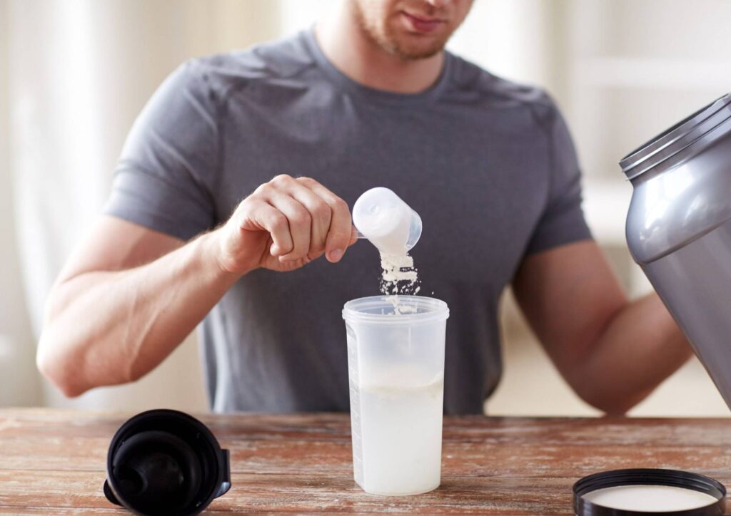 Is Creatine Good for Weight Loss? 3 A man pouring a liquid ingredient into a blender on a kitchen countertop.
