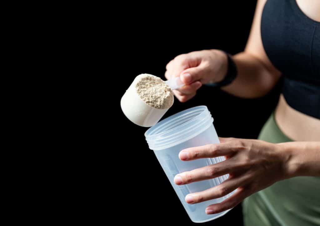 Is Creatine Good for Weight Loss? 11 A woman holds a shaker filled with powder, preparing to mix a drink or supplement.