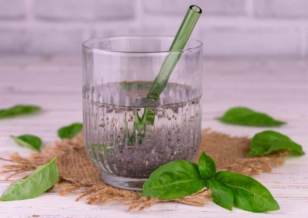 Do Chia Seeds Help With Weight Loss? 12 A clear glass of water with a straw and a green leaf resting on the rim, symbolising freshness and hydration.
