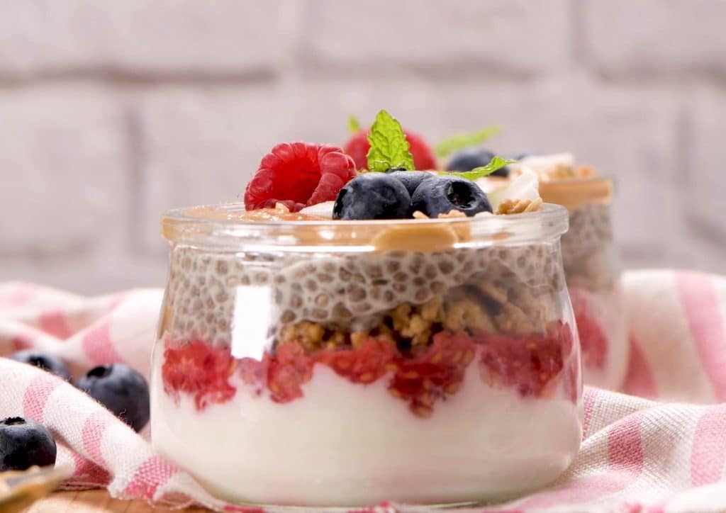 Do Chia Seeds Help With Weight Loss? 13 Chia pudding topped with fresh berries and nuts, served in a clear glass bowl on a wooden table.