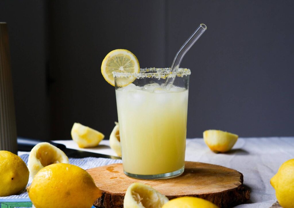 Does Lemon Water Help With Weight Loss? 1 A glass of lemon juice with a straw, garnished with fresh lemon slices on the rim.