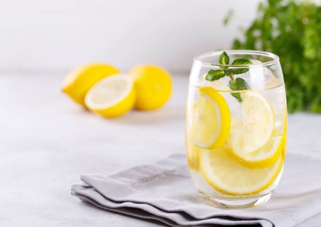Does Lemon Water Help With Weight Loss? 5 A clear glass filled with lemon juice, garnished with fresh lemon slices on the rim.