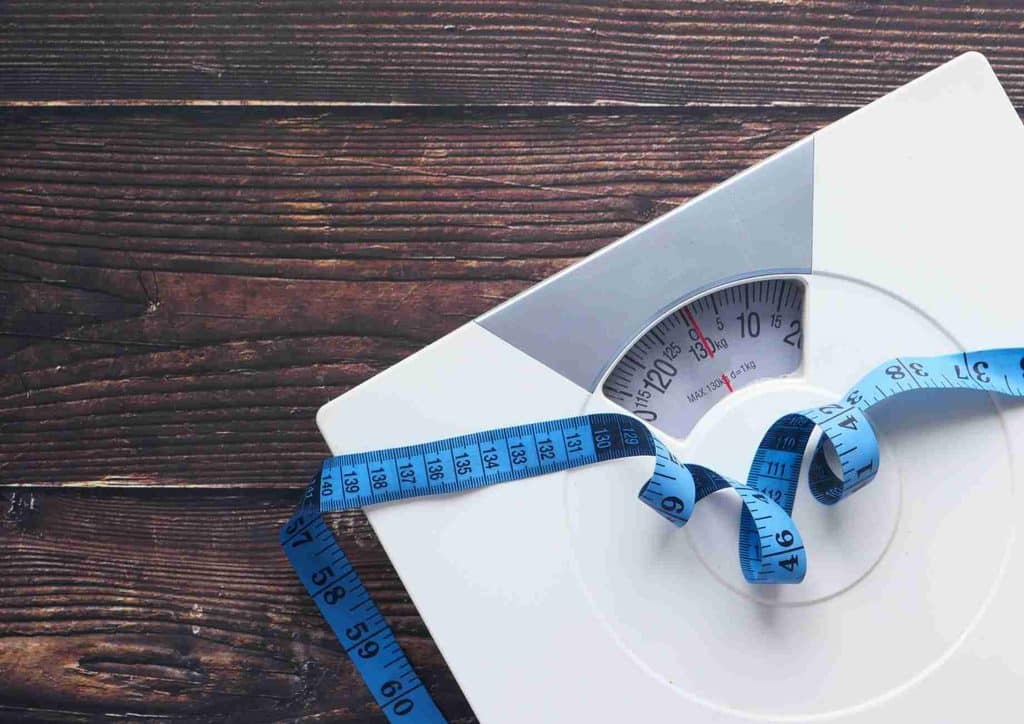 How to Tighten Skin After Weight Loss Naturally 8 A white scale wrapped in blue tape, positioned on a flat surface.
