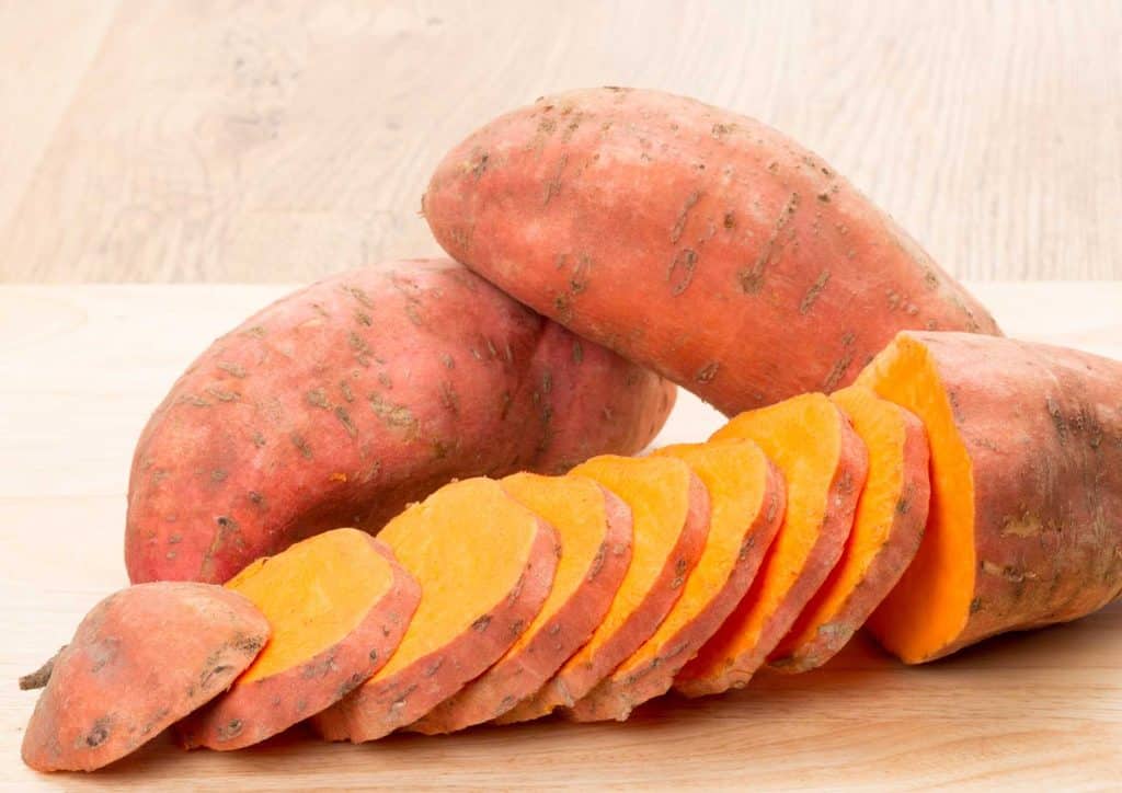 Is Sweet Potato Good for Weight Loss? 1 Sliced sweet potatoes arranged neatly on a cutting board, showcasing their vibrant orange color and smooth texture.