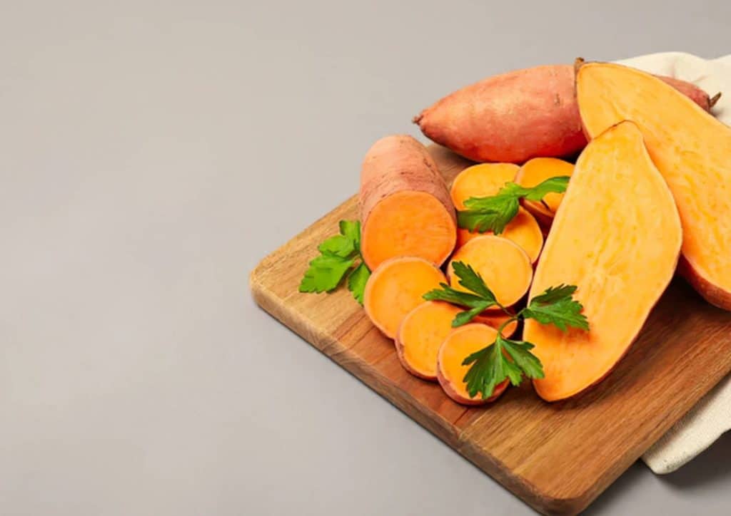 Is Sweet Potato Good for Weight Loss? 9 Fresh sweet potatoes arranged on a wooden cutting board, ready for preparation or cooking.