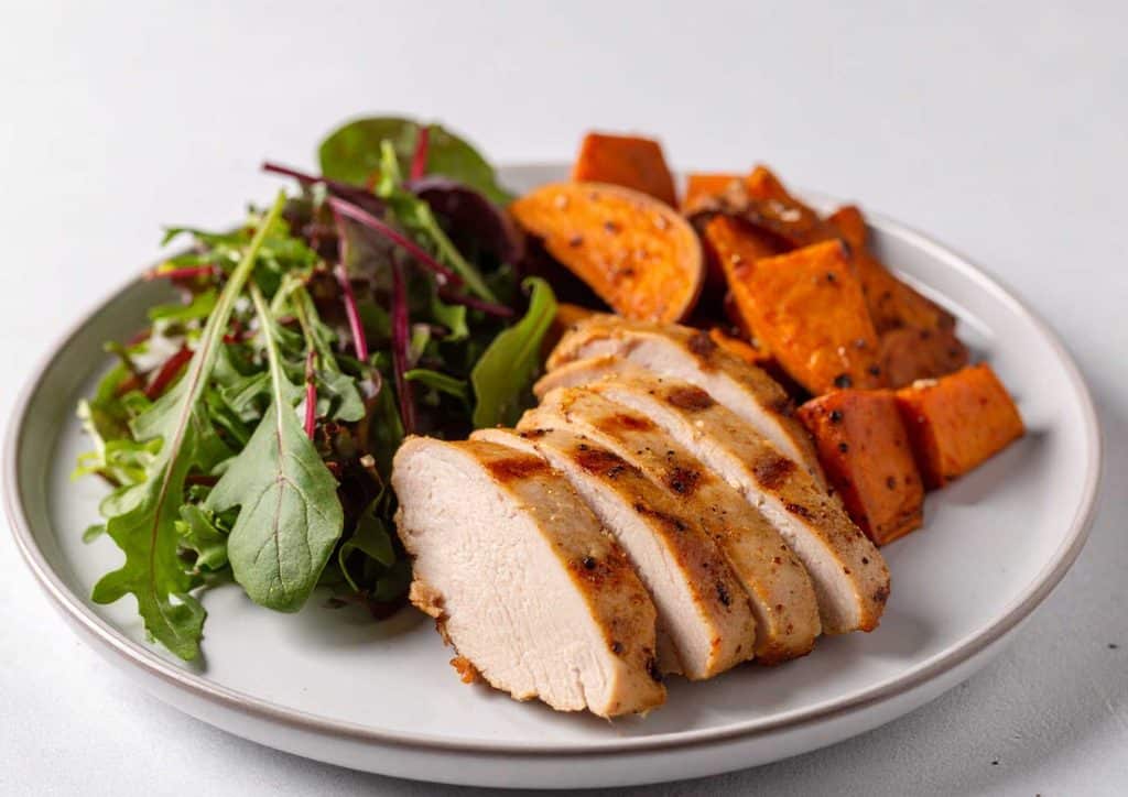 Is Sweet Potato Good for Weight Loss? 16 A plate featuring a grilled chicken breast, roasted sweet potato, and a fresh garden salad.