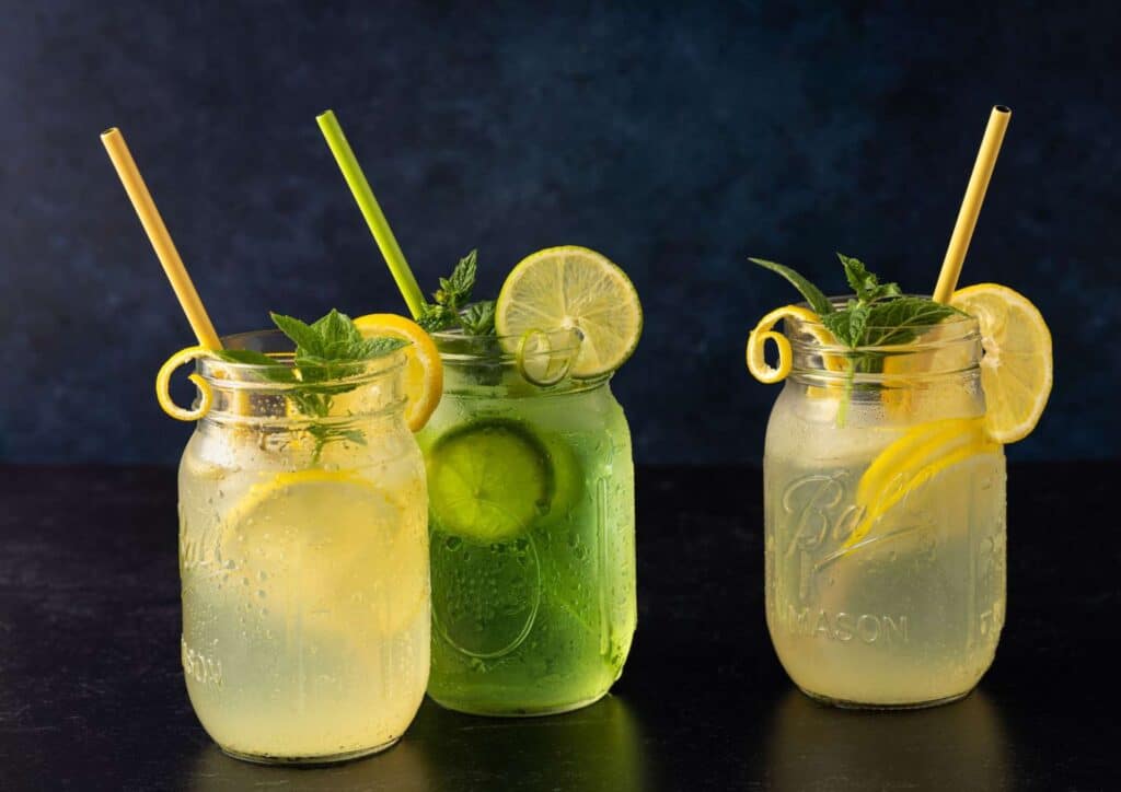 Does Lemon Water Help With Weight Loss? 8 Three jars filled with refreshing lemonade and slices of cucumber, arranged on a wooden surface.