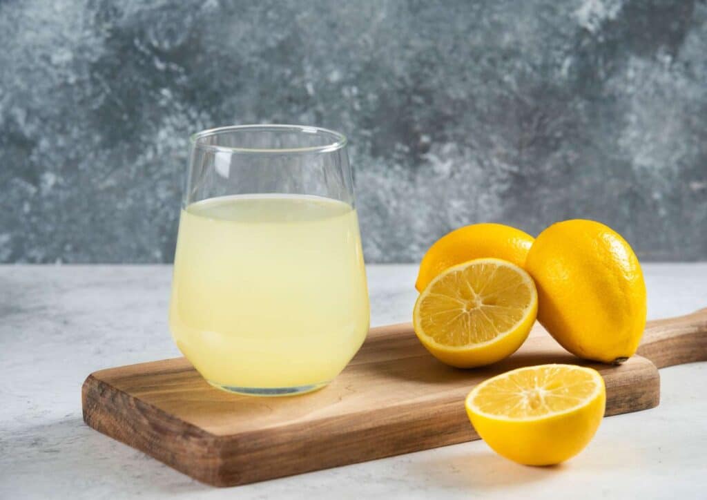 Does Lemon Water Help With Weight Loss? 10 A glass of lemonade beside fresh lemons on a wooden cutting board, showcasing a refreshing summer drink.