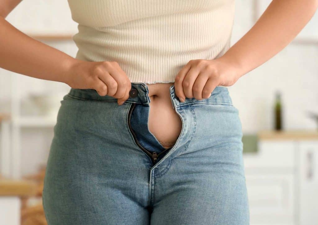 How to Break a Weight Loss Plateau, a Nutritionist's Approach 29 A woman poses confidently, showcasing her stylish jeans in a casual setting.
