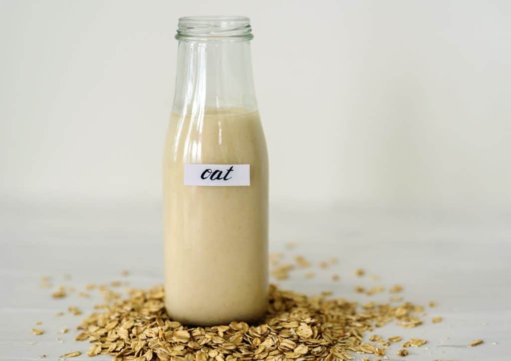 Are Oats Good for Weight Loss? 9 A clear glass bottle filled with creamy oatmeal milk, placed on a wooden surface.