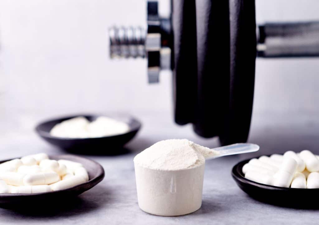 Is Creatine Good for Weight Loss? 6 A white cup placed beside a small pile of white powder on a flat surface.