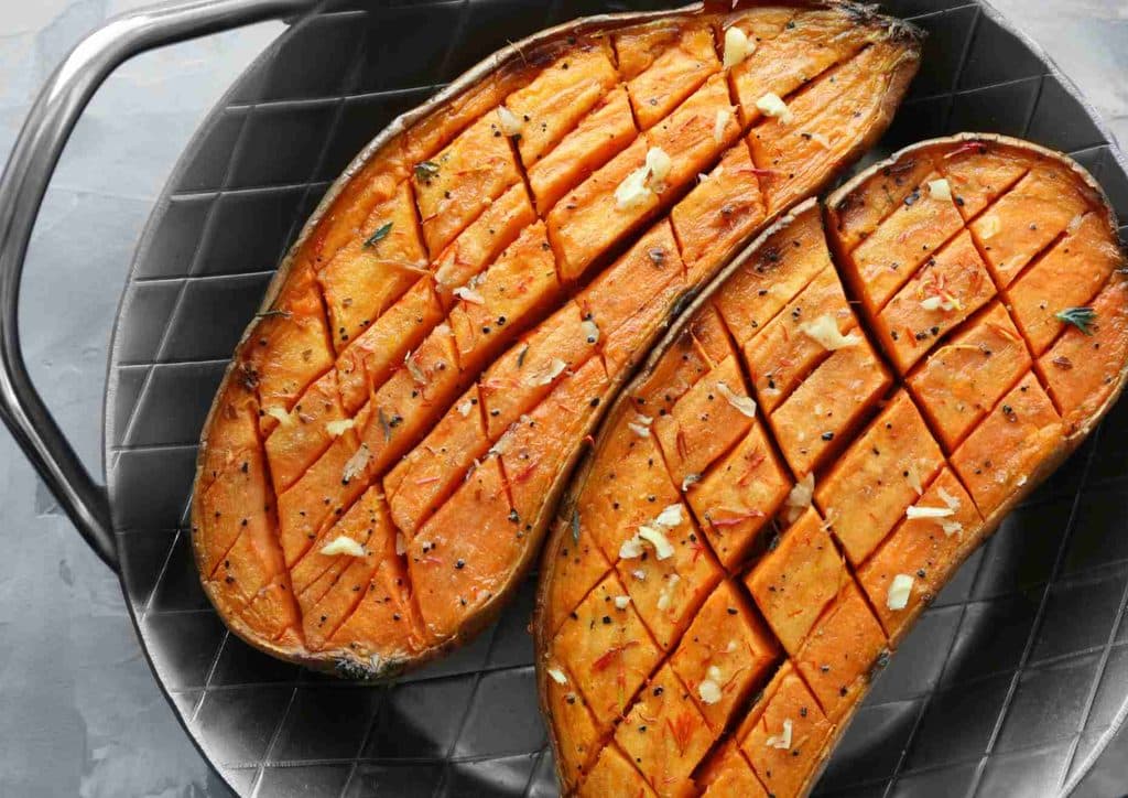 Is Sweet Potato Good for Weight Loss? 21 Two sweet potatoes resting in a pan on a wooden table, showcasing their earthy colour and texture.