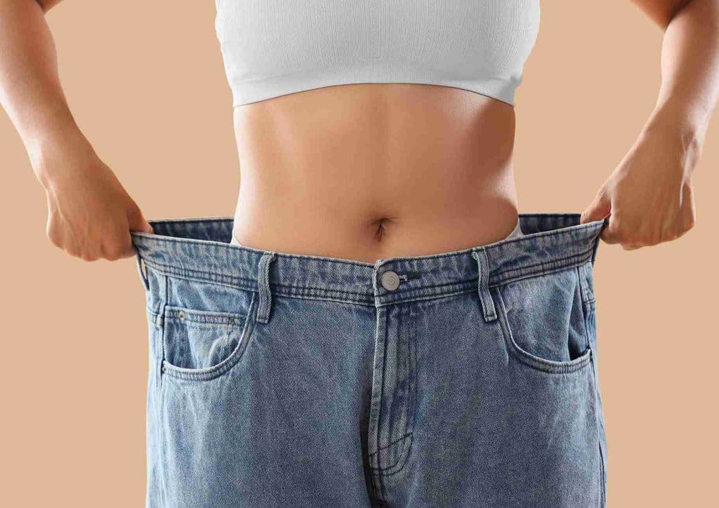 Do Chia Seeds Help With Weight Loss? 16 A woman holds her jeans up, showcasing her stomach and highlighting her outfit in a casual setting.