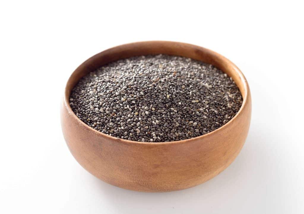 Do Chia Seeds Help With Weight Loss? 17 Chia seeds displayed in a rustic wooden bowl, showcasing their small, round shape and dark colour.