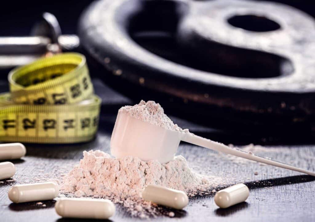 Is Creatine Good for Weight Loss? 2 A scale, measuring tape, and pills arranged on a table, indicating a focus on health and measurement.