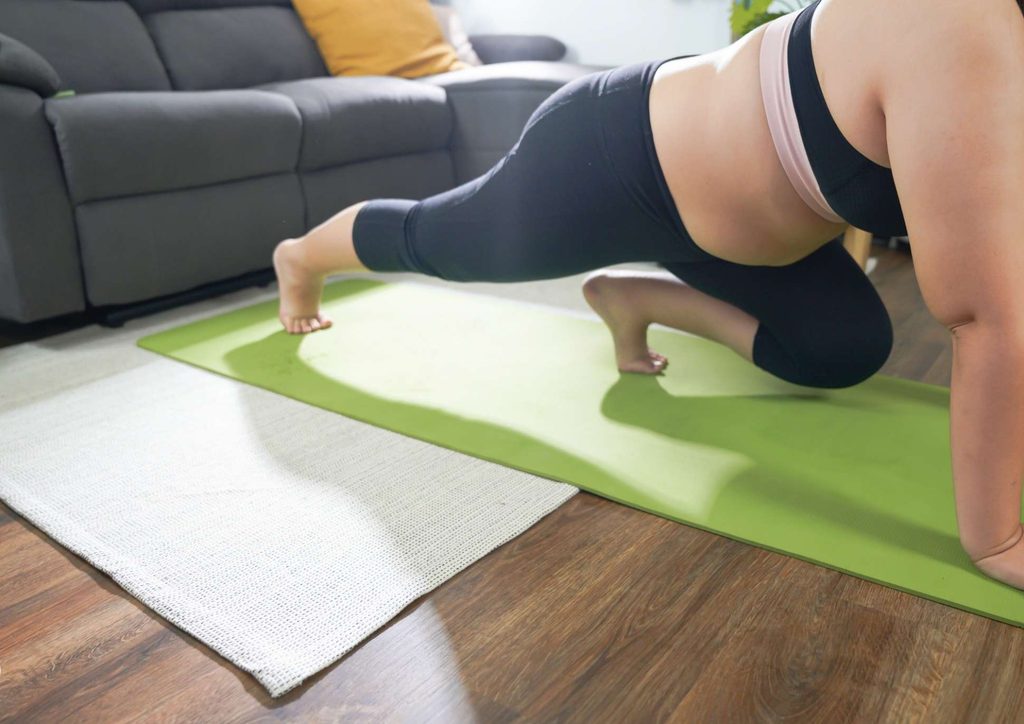 How to Break a Weight Loss Plateau, a Nutritionist's Approach 3 A woman in a black sports bra performs a yoga pose, showcasing balance and flexibility in a serene environment.