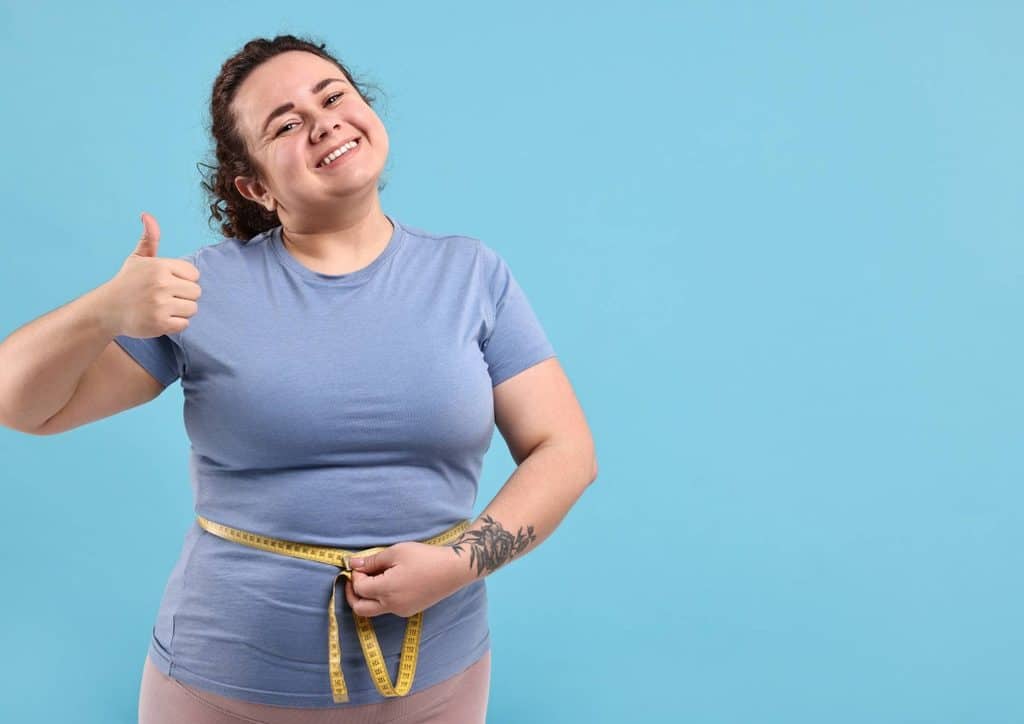 Do Saunas Help With Weight Loss? What Actually Happens 4 A woman measuring her waist with a tape measure, focusing on her fitness or clothing size.