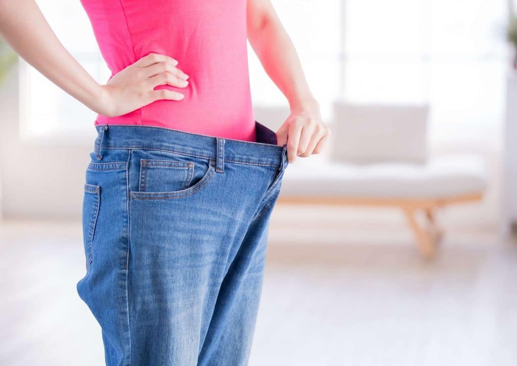 Do Saunas Help With Weight Loss? What Actually Happens 22 A woman in jeans stands with her hands on her waist, looking confidently at the camera.