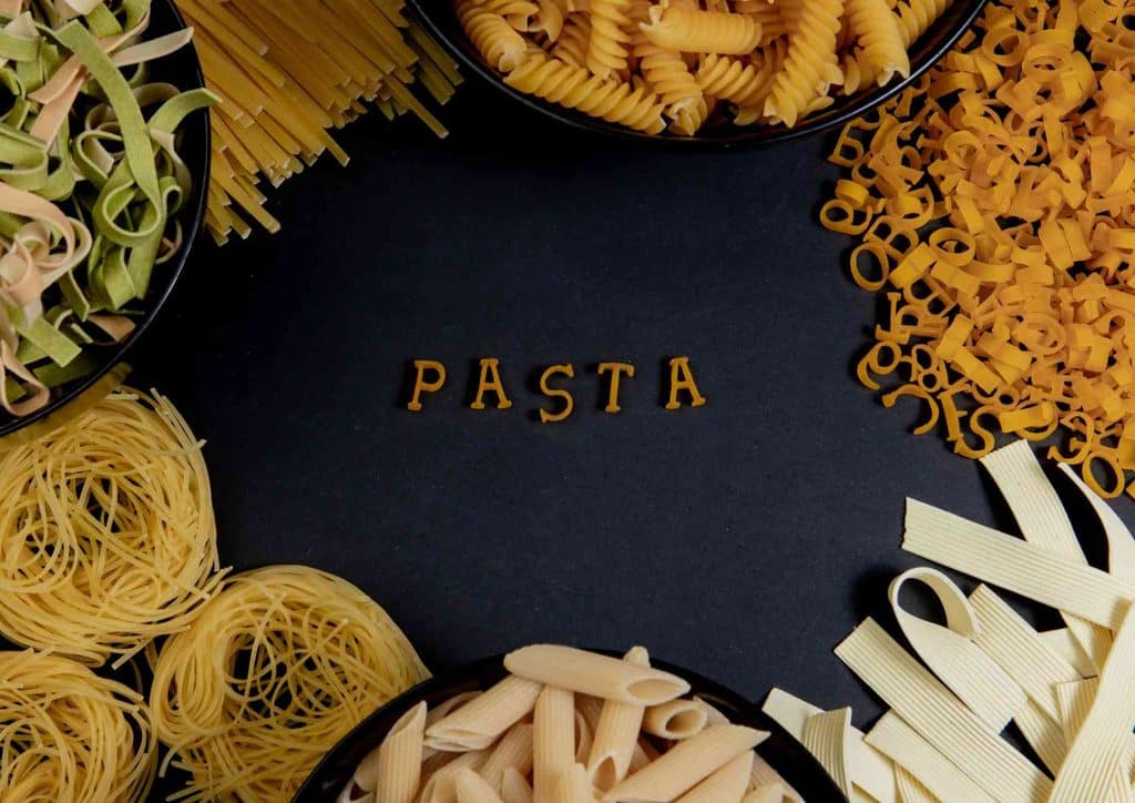 Is Pasta Good for Weight Loss? 1 Various pasta ingredients, including herbs and spices, arranged in bowls on a black background.
