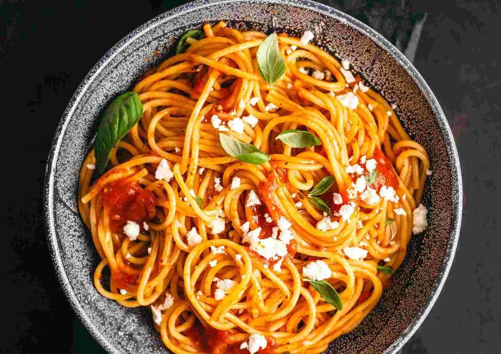 Is Pasta Good for Weight Loss? 10 A plate of spaghetti topped with rich tomato sauce and crumbled feta cheese, garnished with fresh herbs.