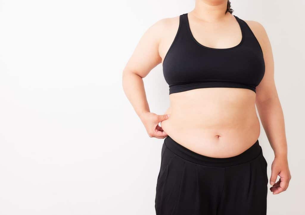 How to Lose Belly Fat: What a Nutritionist Recommends 9 A woman wearing a black sports bra and matching pants, standing confidently with a focused expression.
