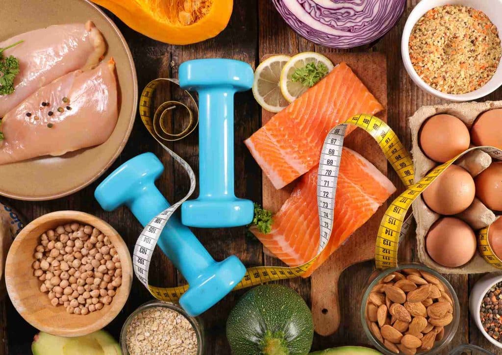 High-Protein Foods for Weight Loss 9 A colourful assortment of foods featuring eggs, fish, nuts, and fresh vegetables arranged on a wooden table.