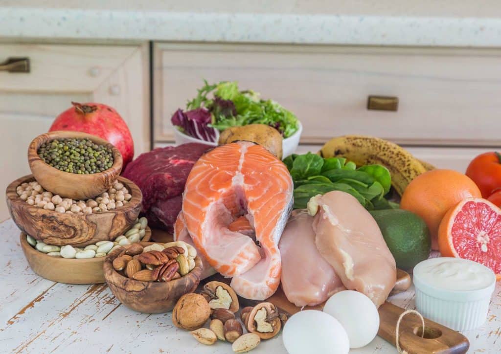 High-Protein Foods for Weight Loss 12 A colourful assortment of foods featuring fish, eggs, fresh vegetables, and various fruits arranged on a table.